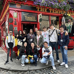 Jóvenes del viaje escolar de InterWay fotografiándose frente a un típico pub de fachada roja en su programa de inmersión lingüística en Europa.