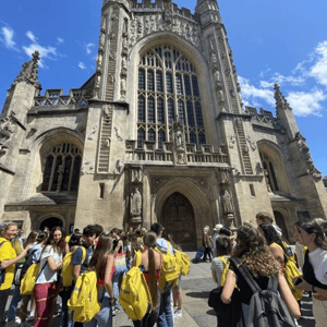Grupo de estudiantes de InterWay con mochilas amarillas frente a la fachada de la Abadía de Bath durante una excursión del curso de inglés en Bath College.