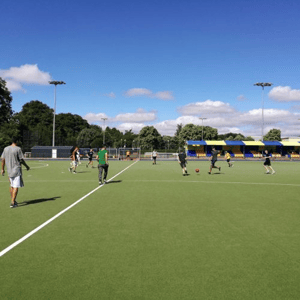 Alumnos del programa de verano de InterWay participando en actividades deportivas en un amplio campo de césped artificial en Bath College.
