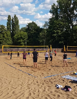 Un grupo de estudiantes del programa deportivo de InterWay entrena y juega un partido en una pista de vóley playa de arena al aire libre en el Reino Unido.