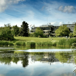 Lago del campus universitario de la University of Bath reflejando el entorno verde y los modernos edificios donde se aloja el curso de InterWay.