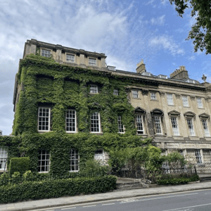 Fachada de un edificio señorial de arquitectura georgiana cubierto de hiedra verde en una calle de Bath, representativo del entorno del curso de InterWay.