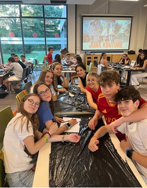 Estudiantes del curso de inglés de InterWay en Blackrock College sonriendo sentados a la mesa durante un taller de Junk Kouture con materiales reciclados.