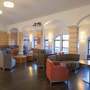 Interior de una amplia sala de estar común con sofás y grandes ventanales en la residencia de estudiantes de Boston College con InterWay.