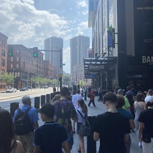 Estudiantes del viaje de idiomas de InterWay paseando en grupo por una concurrida avenida urbana con rascacielos de fondo durante una excursión en Boston.