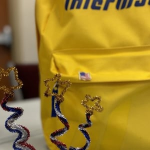Detalle en primer plano de una mochila amarilla corporativa con el logotipo de InterWay durante el programa de verano en Boston.