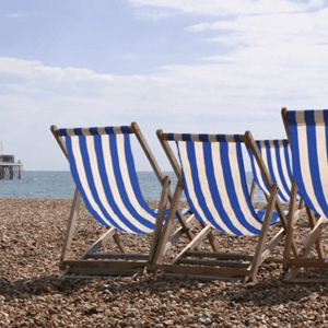 Fila de las tradicionales tumbonas de rayas azules y blancas sobre la playa de piedras de Brighton durante el curso de verano de InterWay en Inglaterra.