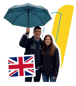 Dos estudiantes de InterWay sonriendo bajo un paraguas con la bandera del Reino Unido, integrados sobre el fondo del muelle Brighton Pier en Inglaterra.