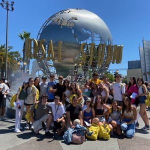 Gran grupo de estudiantes del curso de InterWay posando en la plaza de entrada frente a la icónica bola del mundo giratoria de Universal Studios en Hollywood.