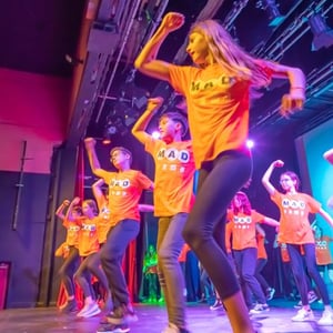 Jóvenes estudiantes del campus de artes escénicas de InterWay realizando una coreografía de baile moderno muy dinámica sobre el escenario.