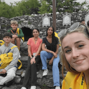 Selfie de una estudiante junto a sus compañeros del curso de inglés en Cork de InterWay, sentados al aire libre junto a una estructura tradicional de piedra.
