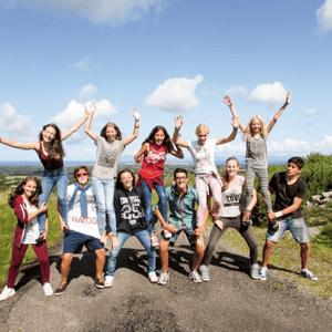 Grupo de jóvenes estudiantes de InterWay del curso de Cork College posando con los brazos en alto de forma divertida en un mirador rodeado de naturaleza.