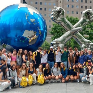 Vista grupal de los estudiantes del curso de inglés de InterWay reunidos para una foto de recuerdo junto a un gran monumento de bola del mundo azul.