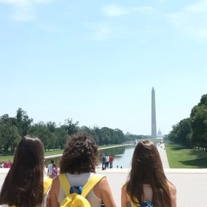 Alumnas de InterWay de espaldas contemplando el estanque de reflejo y el Monumento a Washington en Washington D. C. durante una excursión cultural.