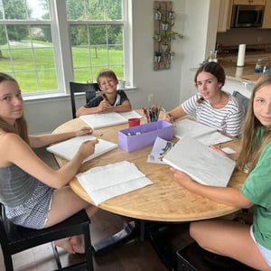 Tres jóvenes estudiantes del viaje de idiomas de InterWay compartiendo una merienda y conversando en la mesa de una casa americana.