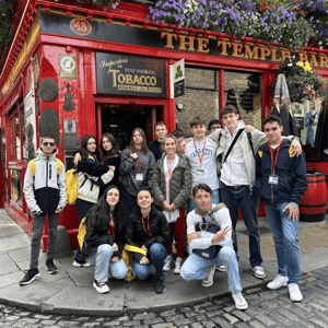 Grupo de estudiantes del curso de inglés Discover Dublin de InterWay posando juntos junto a la icónica fachada roja de The Temple Bar durante una ruta cultural por la ciudad.