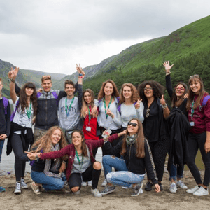 Alumnos del programa Discover Dublin de InterWay saludando y sonriendo en un entorno natural rodeado de montañas durante una excursión a Glendalough, Irlanda.