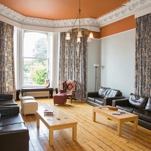 Amplio salón común de la residencia de estudiantes de InterWay en Irlanda, con suelos de madera, sofás de cuero y grandes ventanales de estilo clásico.