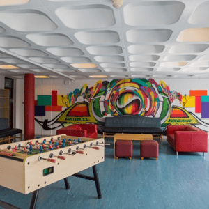 Sala de juegos y zona de ocio para los alumnos de InterWay, con un futbolín, sofás para descansar y un gran mural de arte urbano colorido al fondo.