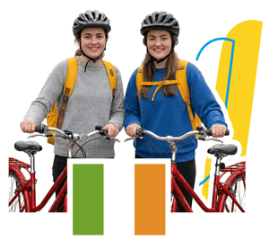 Dos estudiantes del curso de inglés en Dublín de InterWay sonríen con cascos y mochilas amarillas junto a sus bicicletas rojas, en una composición que incluye la bandera de Irlanda y elementos corporativos.