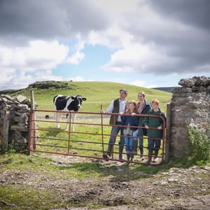 Estudiantes del programa rural de InterWay posando junto a su familia de acogida en un sendero rural junto a un muro de piedra tradicional irlandés.