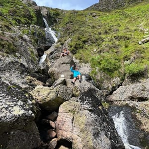 Un estudiante realiza una ruta de senderismo junto a una cascada y zonas rocosas durante el programa de inmersión en Irlanda de InterWay.