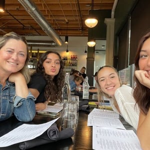 Un grupo de alumnas del curso de InterWay compartiendo una comida y sonriendo en el interior de un local en Irlanda.
