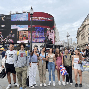 Grupo de estudiantes del curso de verano de InterWay en Londres posando frente a las famosas pantallas luminosas de Piccadilly Circus.