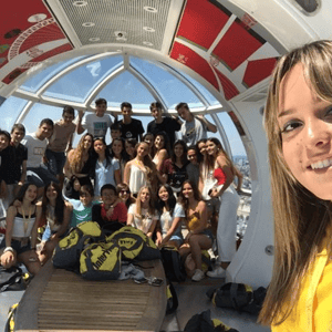 Alumnos del programa de idiomas de InterWay sonriendo y saludando juntos desde el interior de una de las cabinas de la noria London Eye.