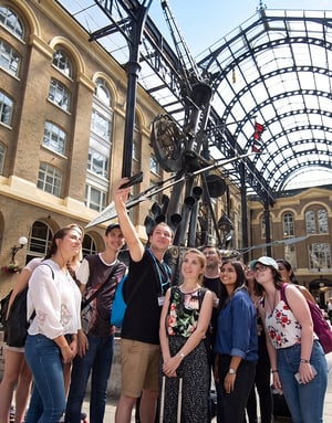 Grupo de estudiantes internacionales del curso de inglés de InterWay en Londres sonríe y posa para un selfie grupal dentro de la histórica galería acristalada de Hay's Galleria.