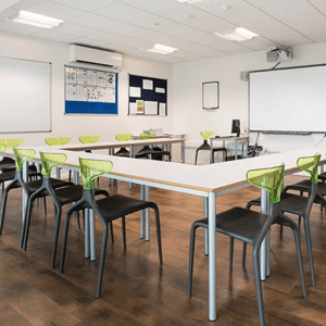 Aula moderna y luminosa con mesas dispuestas en forma de U y sillas ergonómicas, preparada para las clases del curso de inglés en Londres de InterWay.