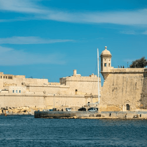 Vista de las antiguas murallas de piedra y la torre de vigilancia de La Valeta sobre el mar Mediterráneo, una de las visitas culturales del programa de InterWay en Malta.