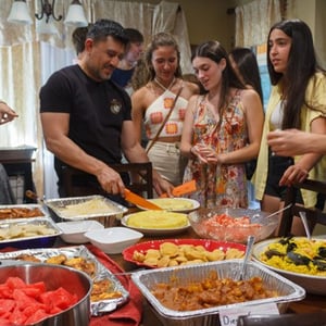 Estudiantes del curso de inglés de InterWay se sirven comida de un buffet casero junto a su familia de acogida estadounidense.