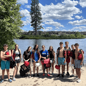 Grupo de jóvenes estudiantes de InterWay posando a la orilla de un río en Oregón durante una actividad de inmersión y naturaleza al aire libre.