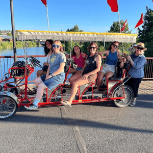 Alumnas del curso de verano de InterWay en Oregón divirtiéndose y paseando juntas en una bicicleta múltiple de cuatro ruedas.