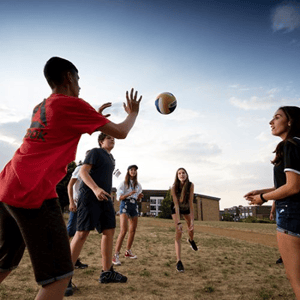 Estudiantes del curso de inglés de InterWay jugando al voleibol en una zona de césped al aire libre durante las actividades de tarde del programa.