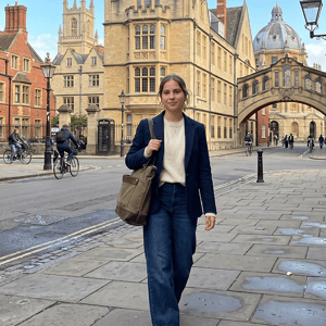 Una estudiante del curso de verano de InterWay caminando por una calle peatonal de Oxford, con el Puente de los Suspiros y los históricos edificios universitarios de fondo.