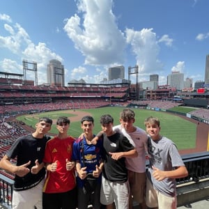 Un grupo de jóvenes estudiantes de InterWay posa en la grada superior de un gran estadio de béisbol americano durante una excursión deportiva de tarde.