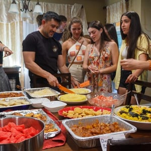 Estudiantes del curso en Seattle de InterWay se sirven comida en un buffet durante una reunión familiar en una casa estadounidense.