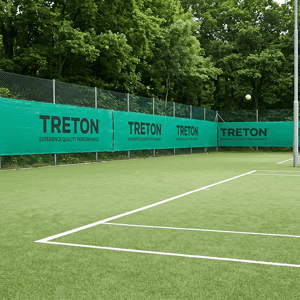 Vista de una pelota de tenis amarilla en el aire a punto de botar cerca de las líneas blancas de una pista de césped artificial durante el campamento deportivo de InterWay.