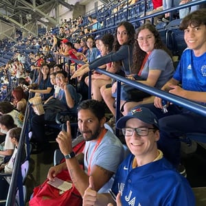Estudiantes del curso de InterWay en Toronto sentados en las gradas animando durante un evento deportivo en Canadá.