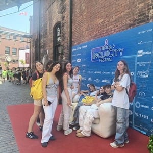 Cuatro alumnas del viaje de verano de InterWay charlan y posan con vestidos blancos en un photocall exterior con alfombra roja.