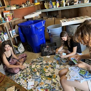 Estudiantes del programa de voluntariado de InterWay en el Sur de California sentados en el suelo mientras clasifican y organizan materiales para un proyecto solidario.