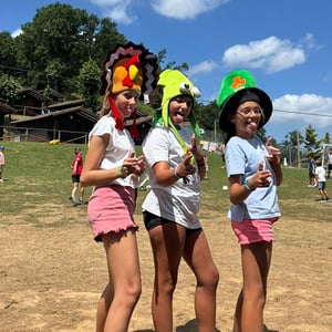 Niñas sonrientes disfrazadas con sombreros coloridos participando en las actividades y juegos al aire libre de un campamento de verano de interway