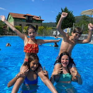 Estudiantes jóvenes saltando y disfrutando en una piscina durante las actividades acuáticas de verano de Interway