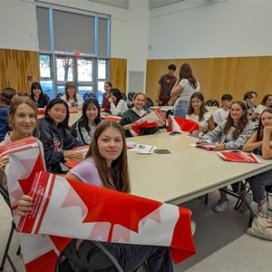 Alumnos de Interway reunidos en un aula canadiense mostrando la bandera de Canadá durante una actividad escolar