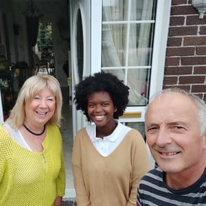 Estudiante de Interway sonriente junto a su familia de acogida irlandesa en la entrada de su casa de integración